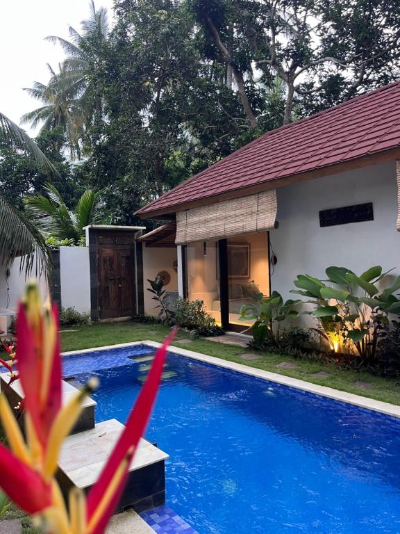 a villa with a swimming pool in front of a house at Villa Semoga in Tanjung