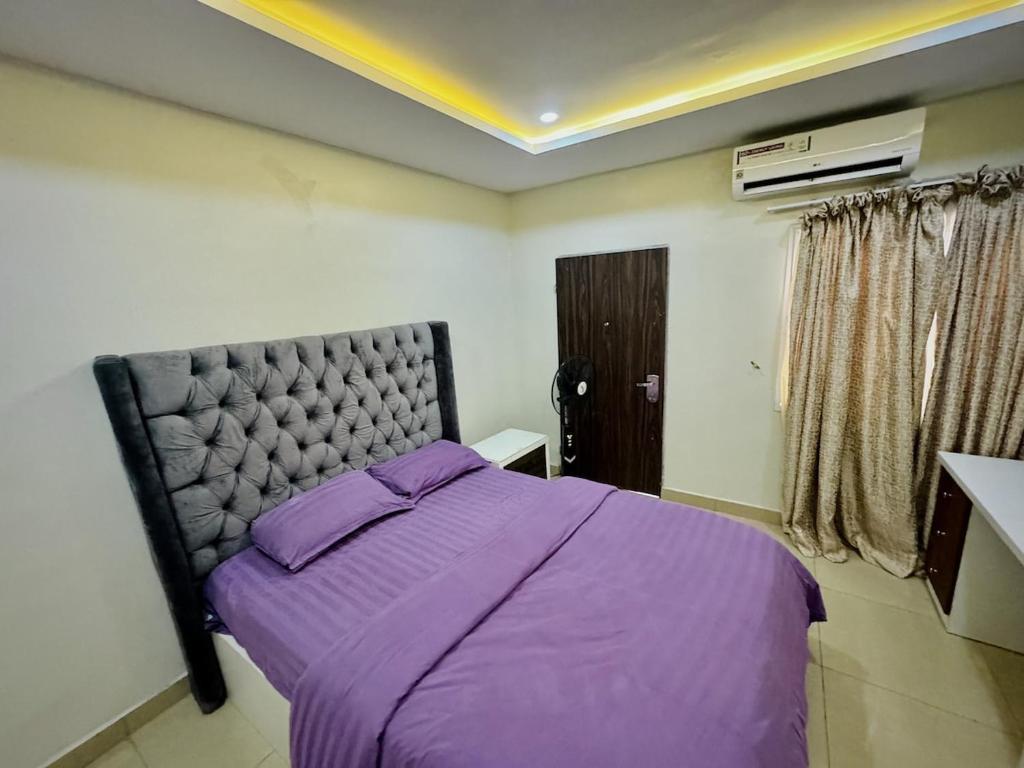 a bedroom with a bed with purple sheets and a window at Abuja Circa Suite in Abuja