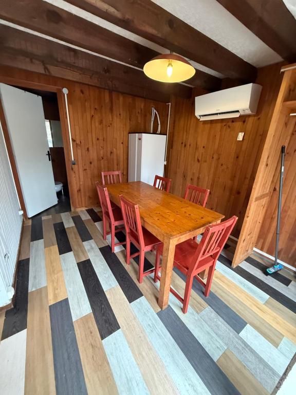 a dining room with a wooden table and red chairs at LK gîte la forêt in Chénérailles