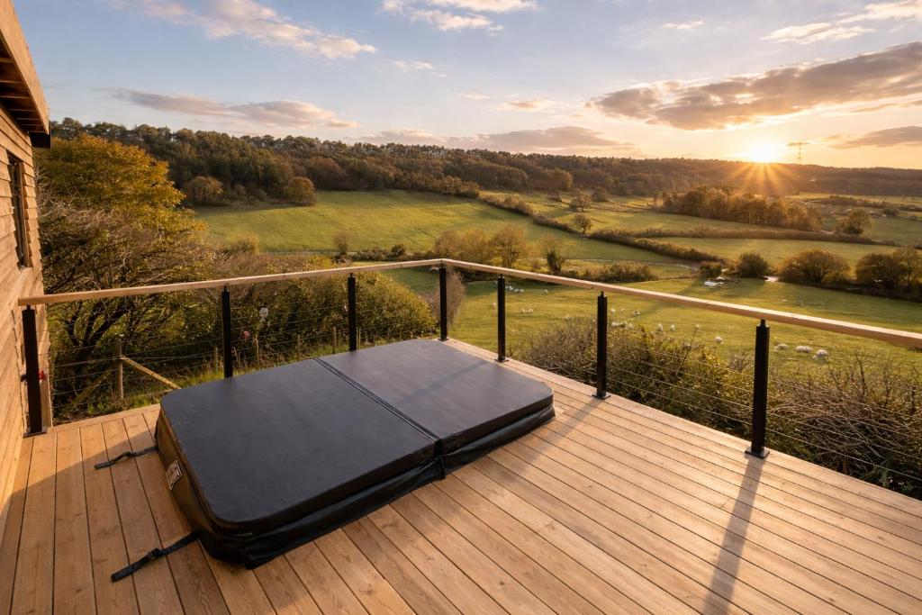 a bed sitting on a wooden deck with the sunset at Luxury Shepherds Hut with Hot Tub Valley Views in Scarborough