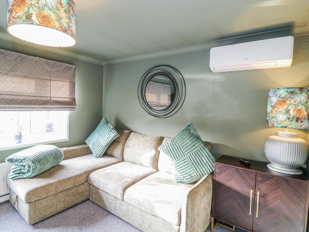 a living room with a couch and a mirror at The Nest Lodge 55 in Grantham