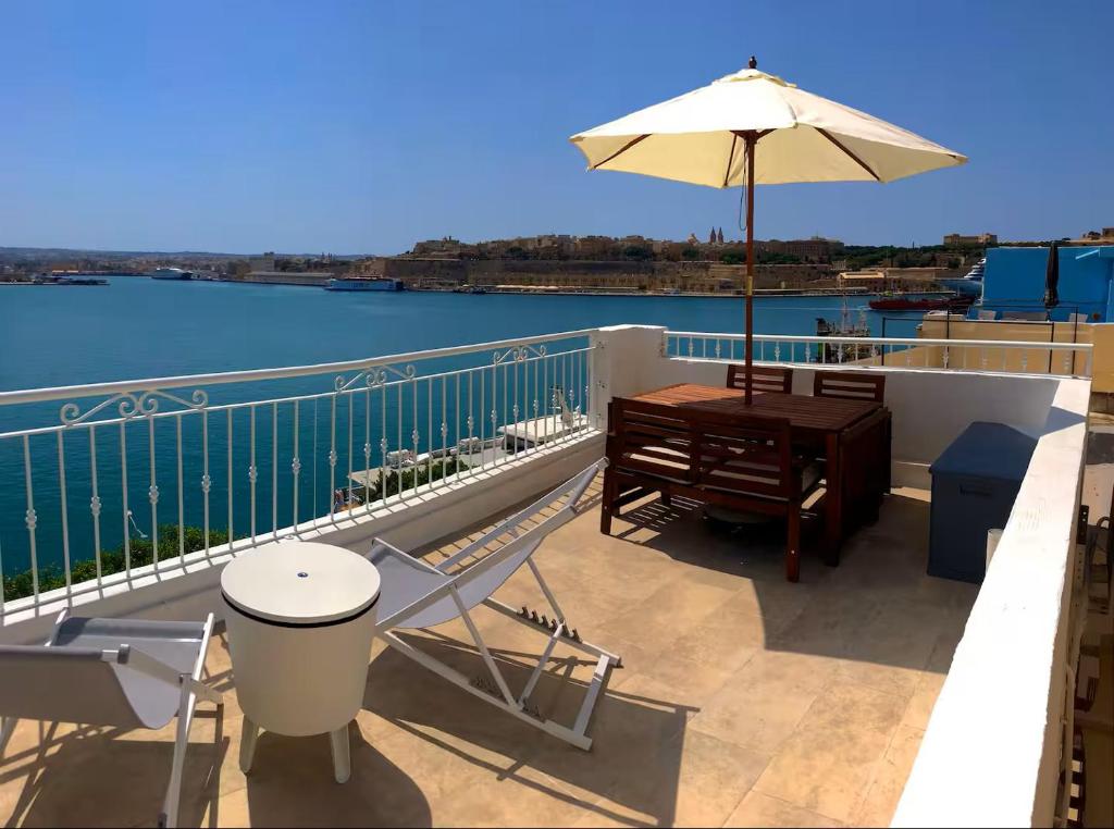a balcony with an umbrella and a table and chairs at Sea Balcony House in Senglea