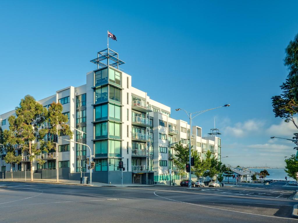 an apartment building with a flag on top of it at Waterfront (Yarra St) by Gold Star Stays in Geelong
