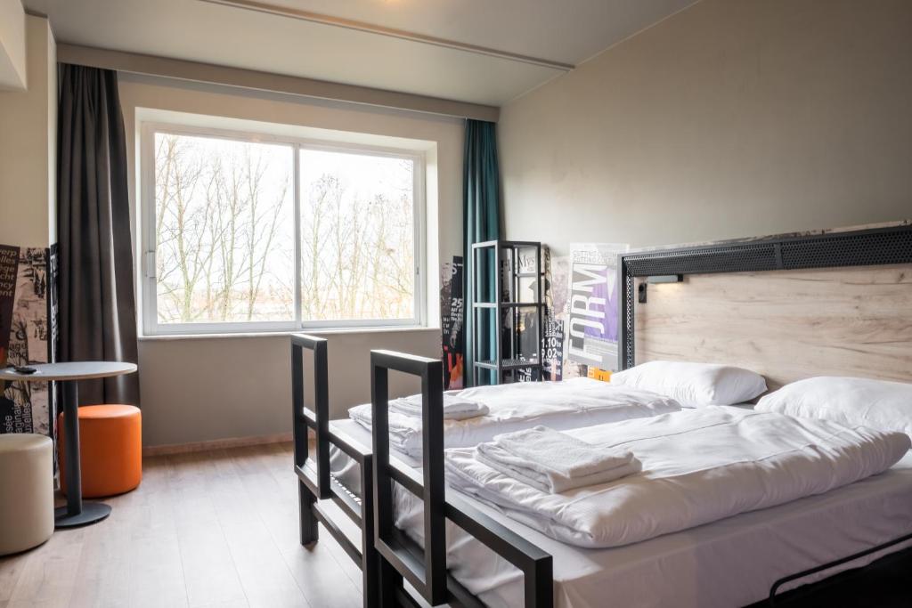 a bedroom with two beds and a large window at a&o Brussel Centrum in Brussels