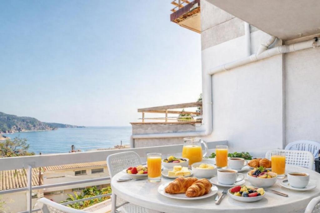 a table with breakfast food and orange juice on a balcony at Cala Paradiso in Tossa de Mar