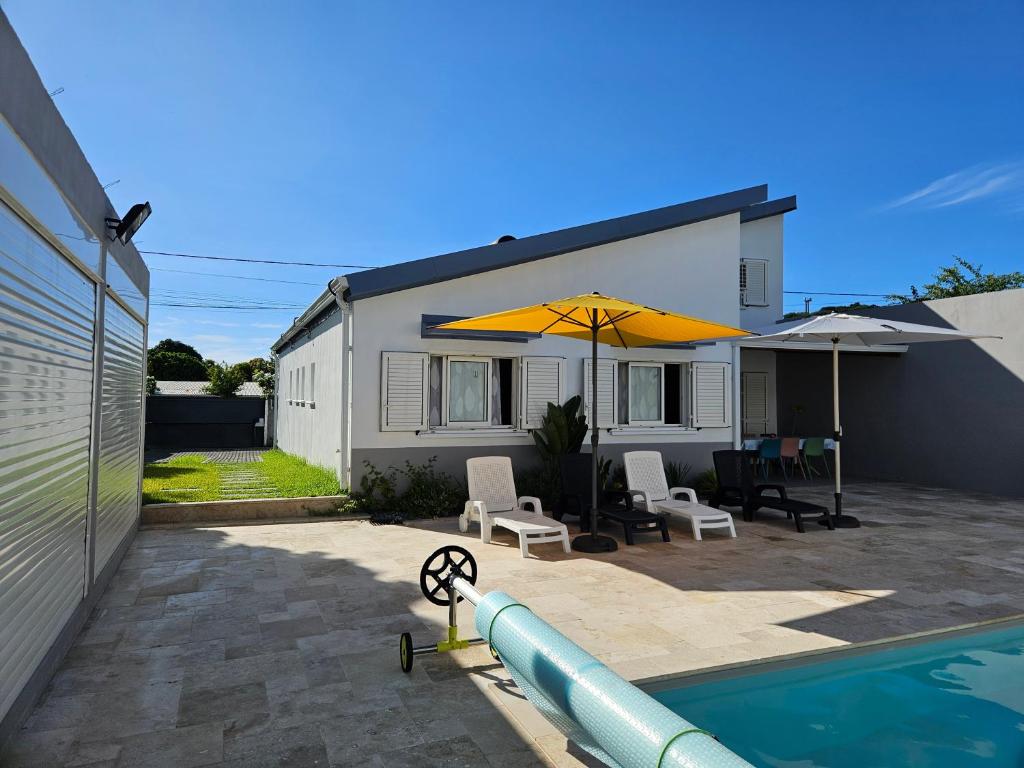 a backyard with a pool and a house with an umbrella at Villa Capucine in Saint-Paul