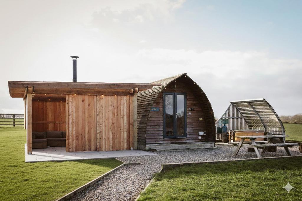 a small wooden cabin in a field with a bench at Sedgewell Barn by Wigwam Holidays in Northallerton