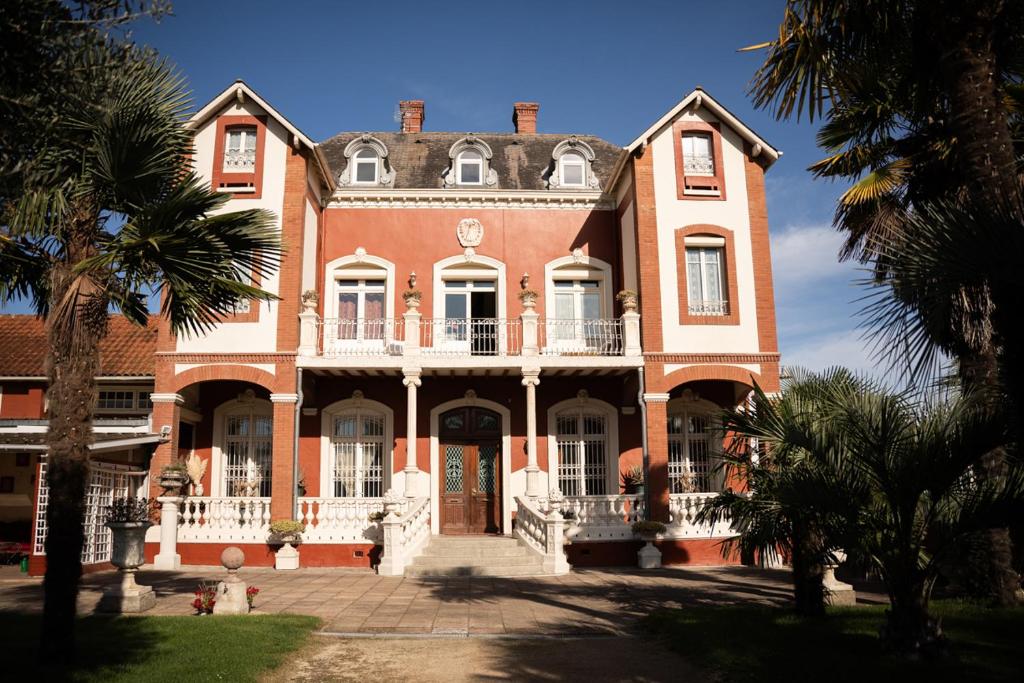 a large red brick house with a balcony at La Maison Coloniale - 15 Personnes - Piscine in Artagnan