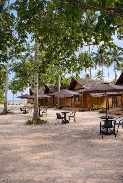 a group of tables and chairs with umbrellas at Sirem Beach Resort in Puerto Princesa City