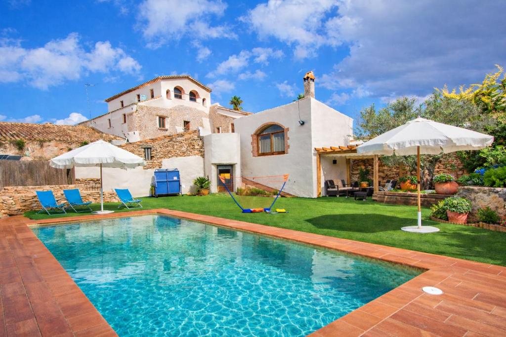 a villa with a swimming pool in front of a house at Catalunya Casas Captivating Villa in the Vineyard close to Sitges in Bisbal del Penedès