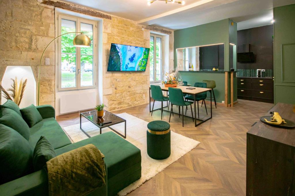 a living room with a green couch and a kitchen at Charmant appartement - L'émeraude in Fontenay-le-Comte