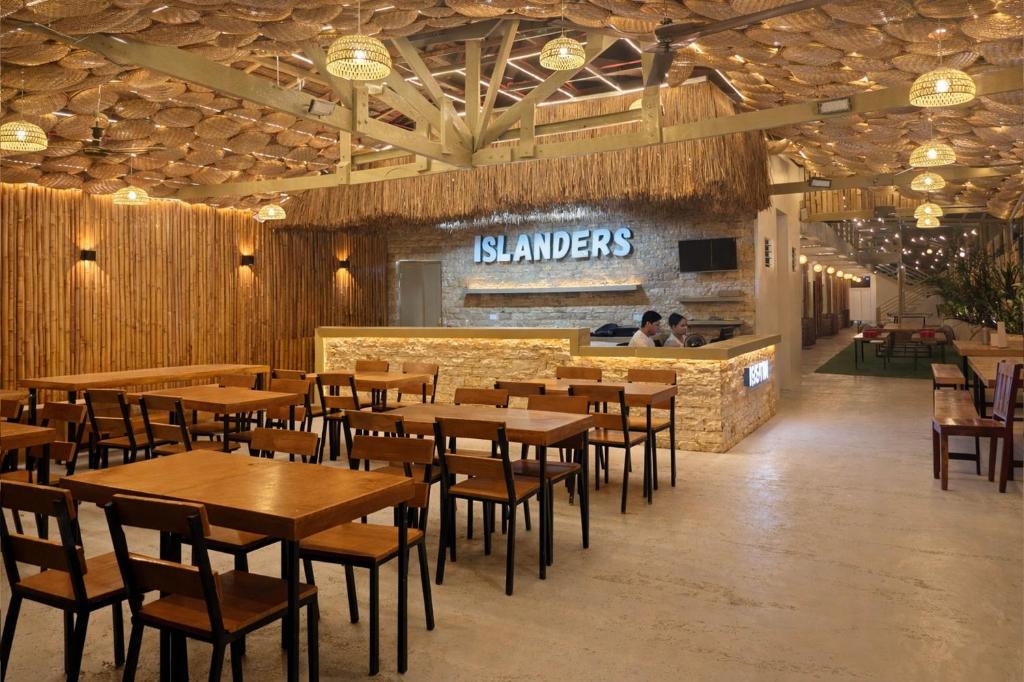 a restaurant with wooden tables and chairs and a counter at Islanders Hostel Siquijor in San Juan