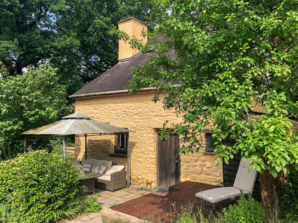 a small brick building with a gazebo and chairs at Ynywsen Dairy Flat in Nantgaredig