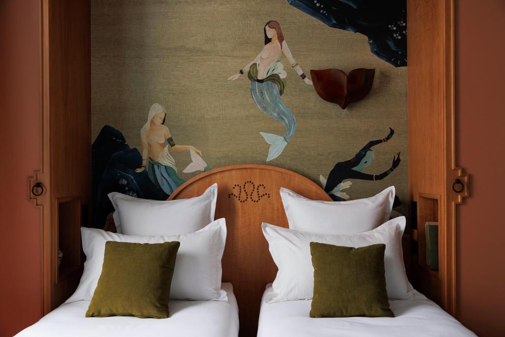 two beds in a hotel room with a painting on the wall at Babel Lille Centre in Lille