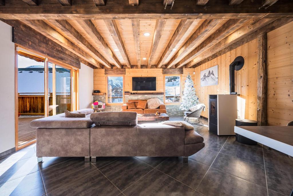 a living room with a large couch and a television at Chalet Liloo sous la neige in Saint-Sorlin-dʼArves