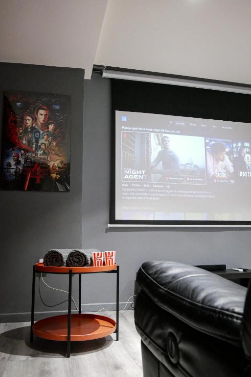 a living room with a table and a projection screen at Suite CinéRoom à 25 min de Paris in Franconville
