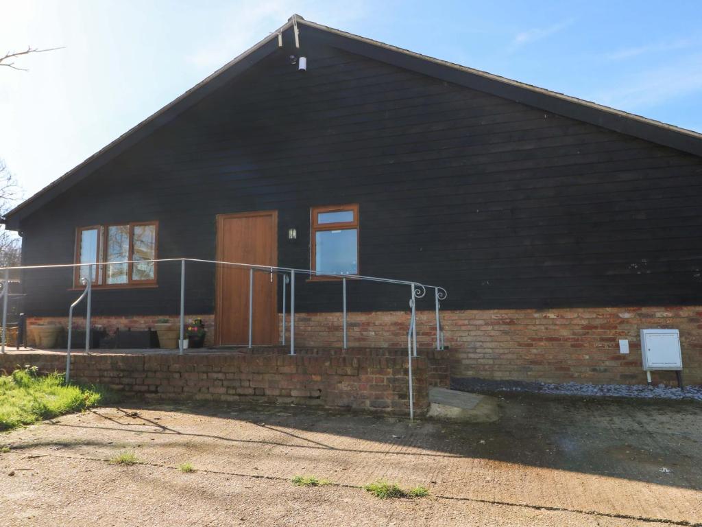 a black brick house with a porch and a door at Bluebell Cottage in Maidstone