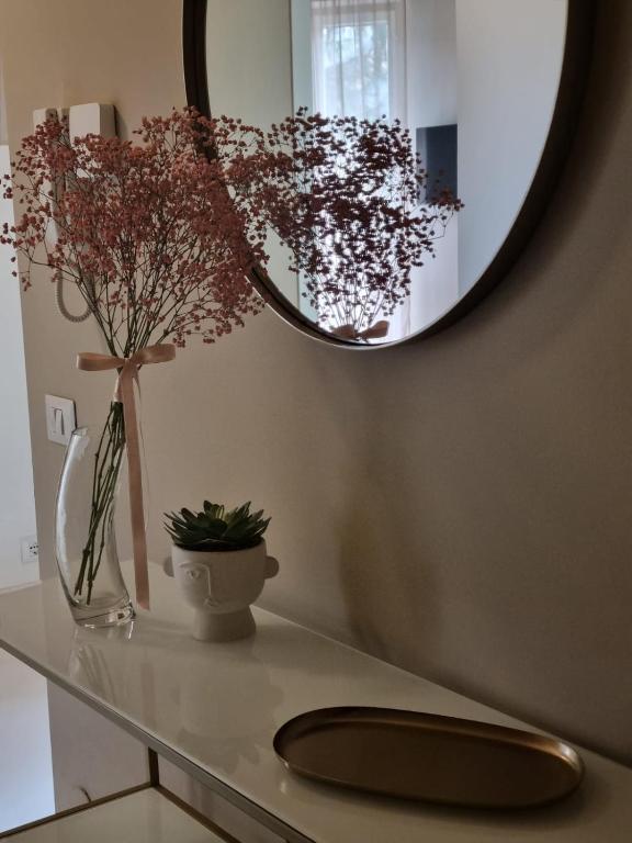 a bathroom counter with a mirror and a vase with flowers at TM My Home in Novara