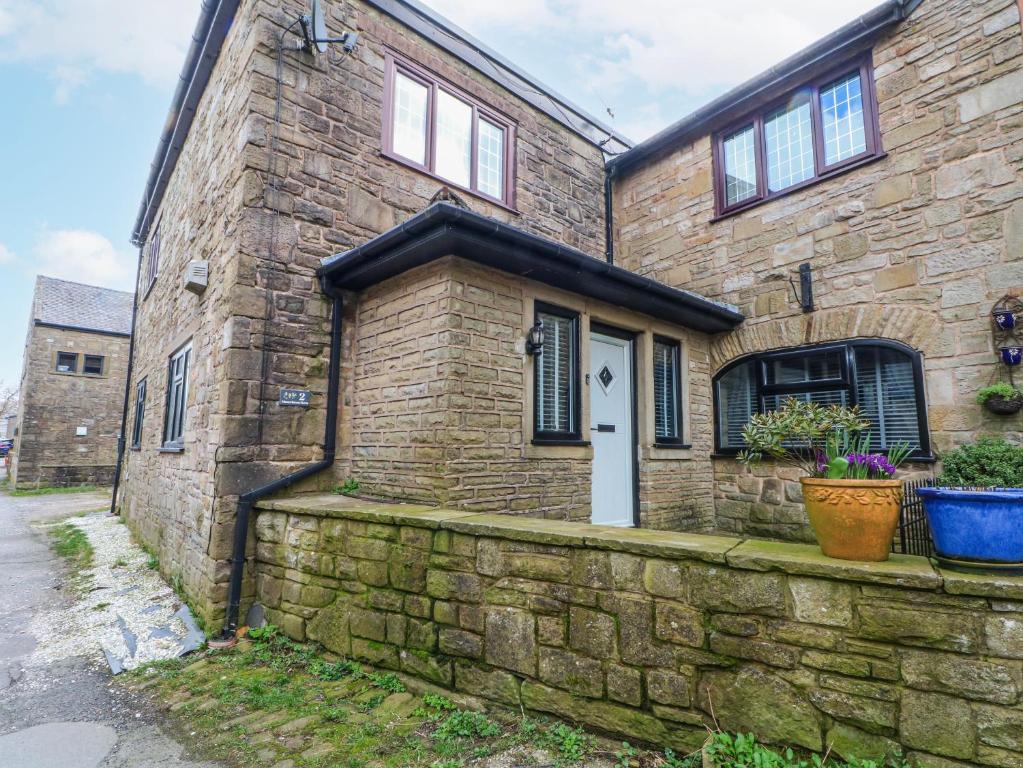 a brick house with a white door and a stone wall at 2 Manorhouse Farm in Rochdale