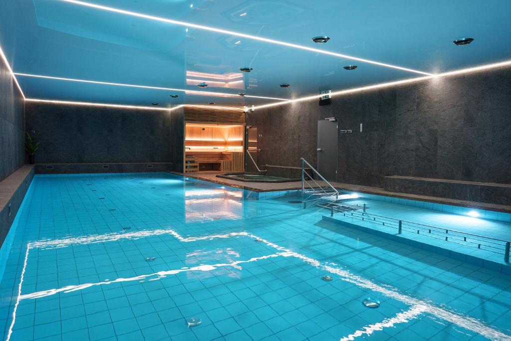 a large swimming pool in a building with blue lights at Hotel Reśliński in Grodzisk Wielkopolski