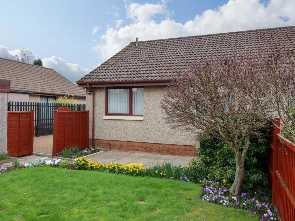 a house with a fence and a yard with flowers at 48 Edenbank Road in Cupar