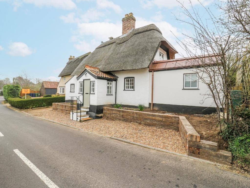 a white house with a thatched roof on the side of the road at The Old Smithy in Cambridge