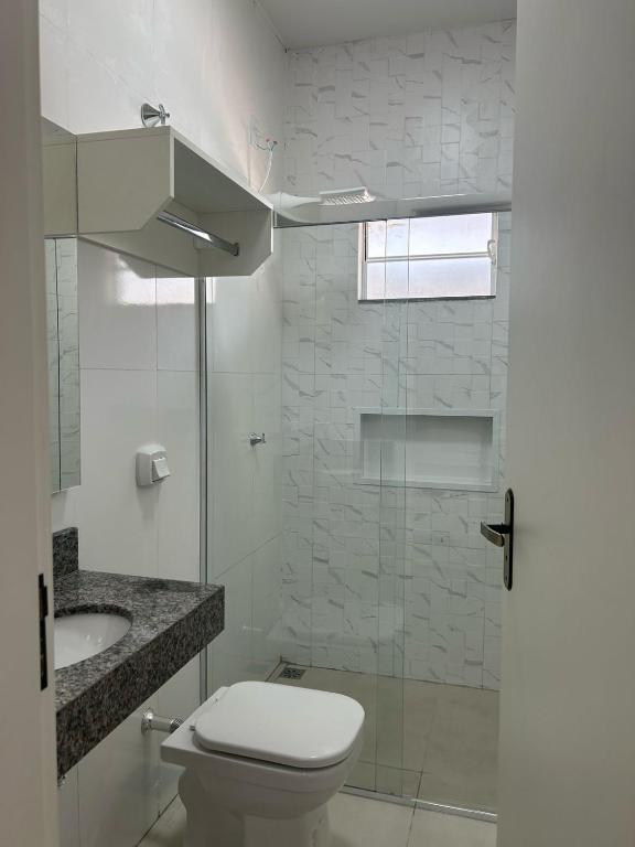 a bathroom with a toilet and a glass shower at Studio J&C 01 in Primavera do Leste