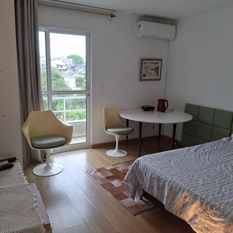 a bedroom with a bed and a table and chairs at Quarto aconchegante in Curitiba