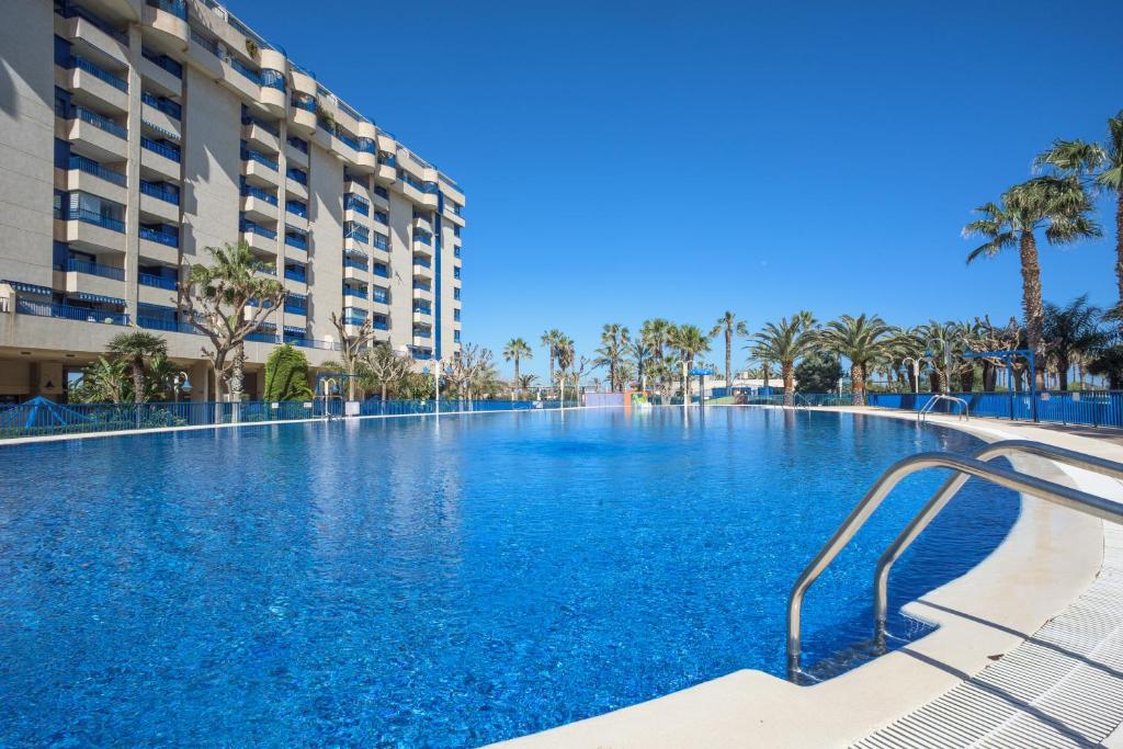 a large swimming pool with palm trees and buildings at Holiday Apartment Patacona Beach in Valencia