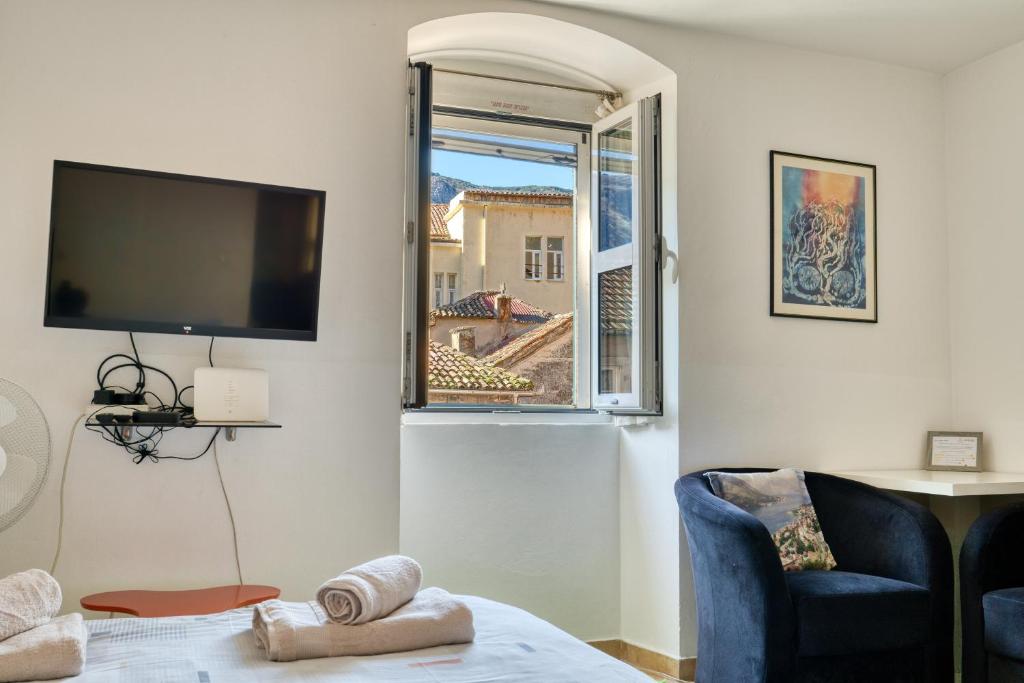 a living room with a tv and a chair and a window at Old Town Boskovic Apartment in Kotor