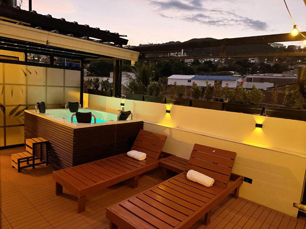 a rooftop patio with a hot tub and two benches at HOTEL 9.5 SAN FERNANDO in Cali