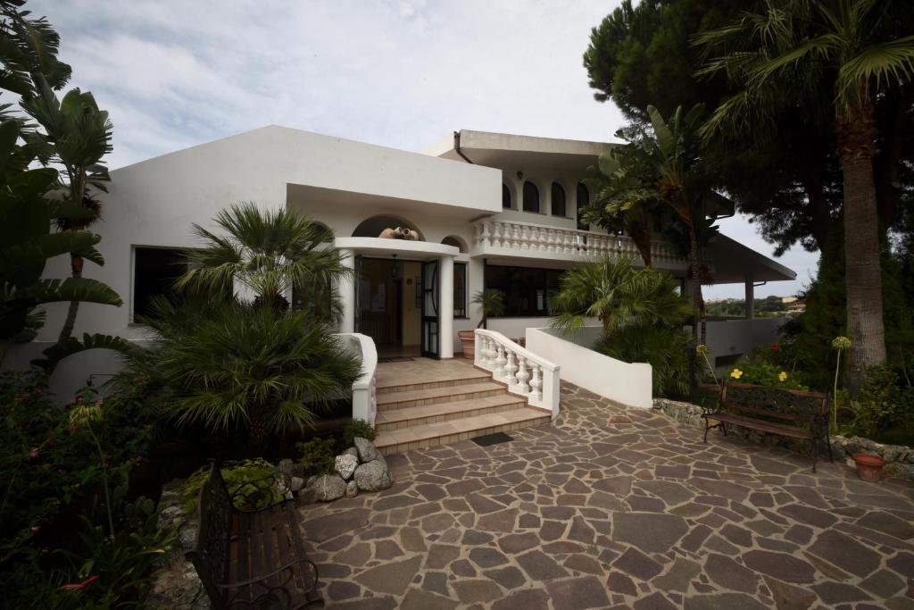 a white house with a staircase and palm trees at Villaggio Pineta Petto Bianco in Capo Vaticano