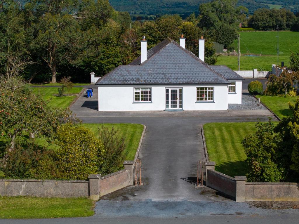 a white house with a driveway in front at Ballyneill Farmhouse in Carrick-on-Suir