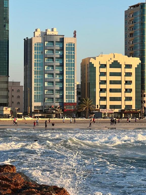 a group of people on a beach with buildings at Mermaid Beach Hotel LLC in Ajman 