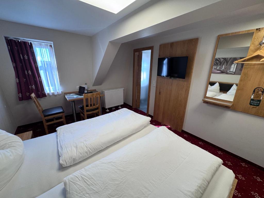 a hotel room with two beds and a table and a mirror at Doppelzimmer 11 in Heidenheim