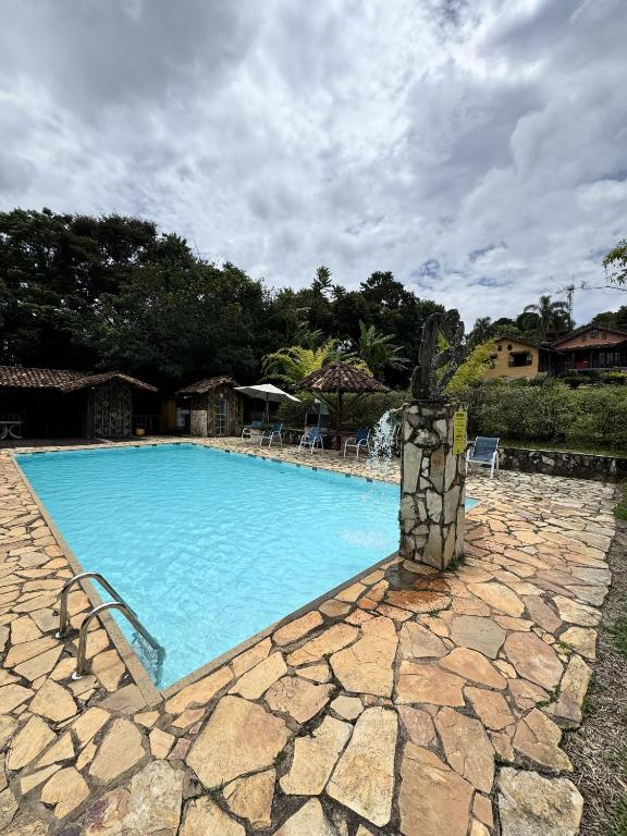 a large blue swimming pool with a stone walkway at Capricho Asturiano in Santo Antônio do Leite