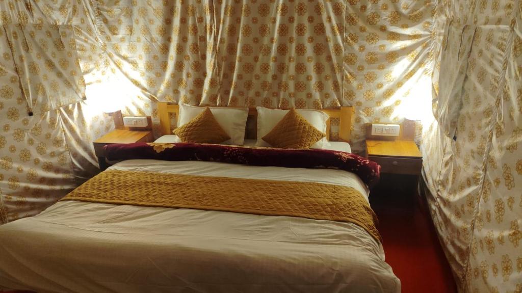 a bed in a room with curtains and a window at Charming Lake View Camp in Bhīm Tāl