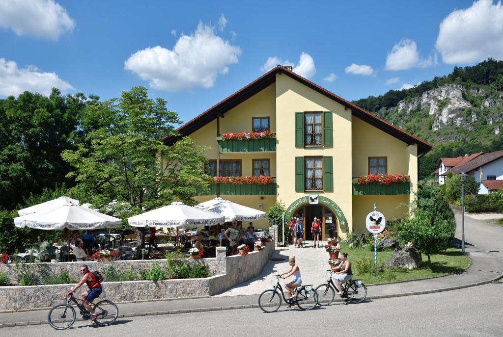 Leute, die vor einem gelben Gebäude Fahrrad fahren in der Unterkunft Landhotel zum Raben in Kipfenberg
