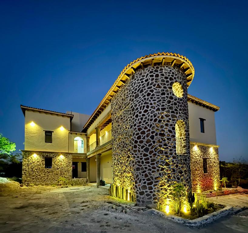 a house with a large stone wall with lights on it at Hotel Suites Piamonte in Bernal