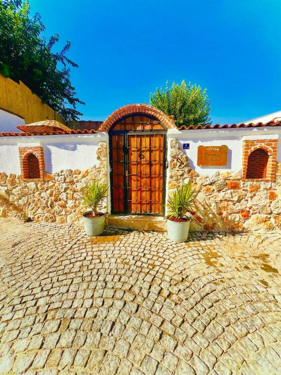 a stone house with a gate and plants in front of it at Adyton Guest House in Didim