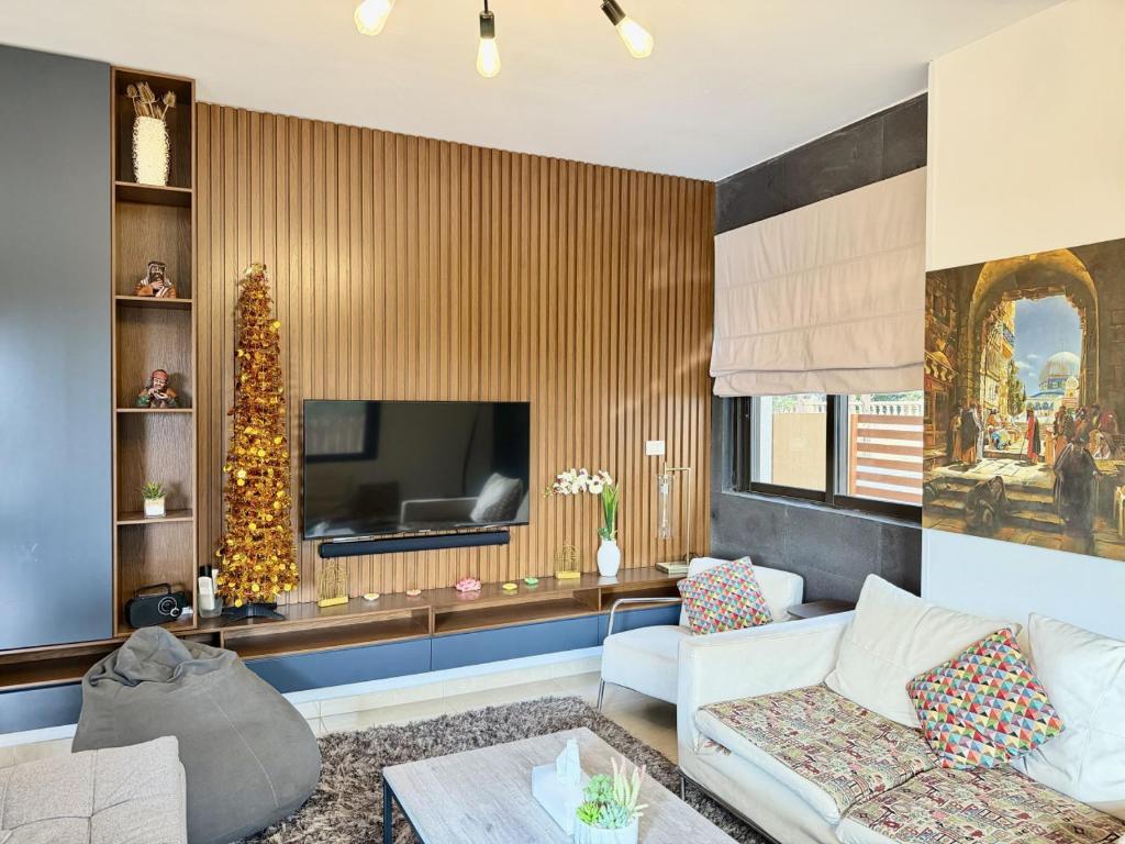 a living room with a couch and a television at Les Voiles Kfar Aabida in Fad‘ūs
