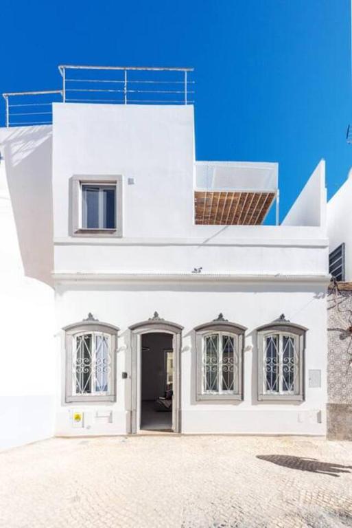 a white house with two windows and a door at Casa Sala - Private Rooftop Swiming Pool in Olhão