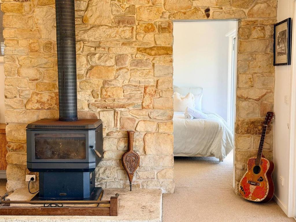 a room with a stone wall with a wood stove at Shorebreak Port Campbell in Port Campbell