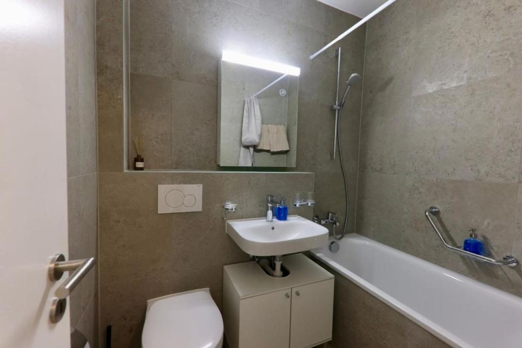 a bathroom with a sink and a toilet and a bath tub at Chailly The Minimalist Lausanne in Lausanne