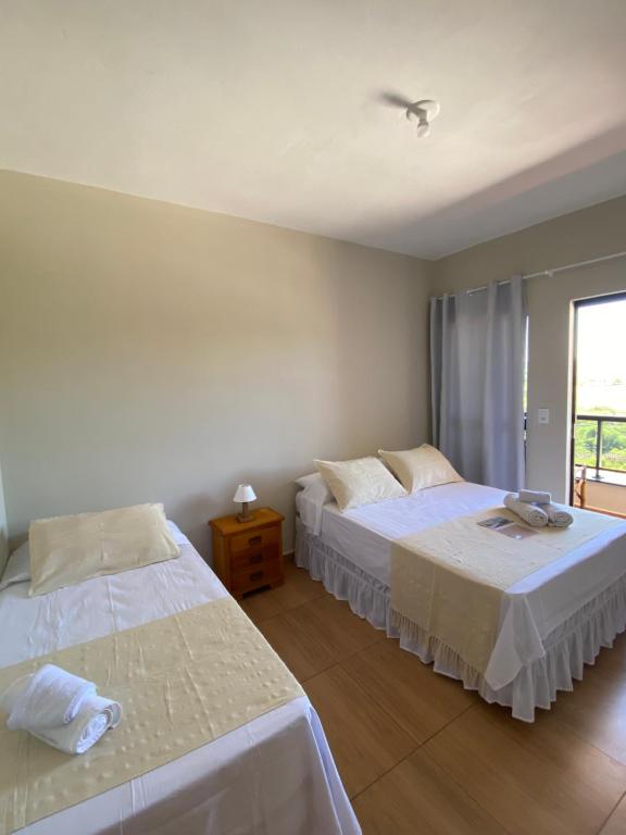 a bedroom with two beds and a window at Casa Portal Carrancas in Carrancas