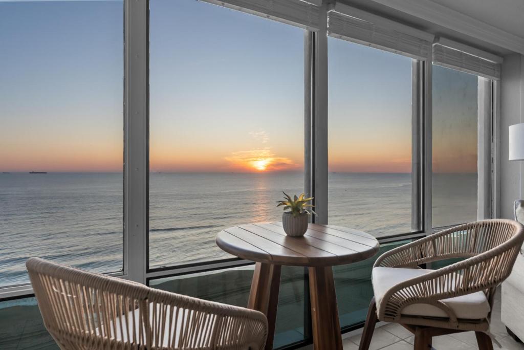 a table and chairs in a room with a view of the ocean at New Beachfront Condo Pool Surfing Fishing in Virginia Beach