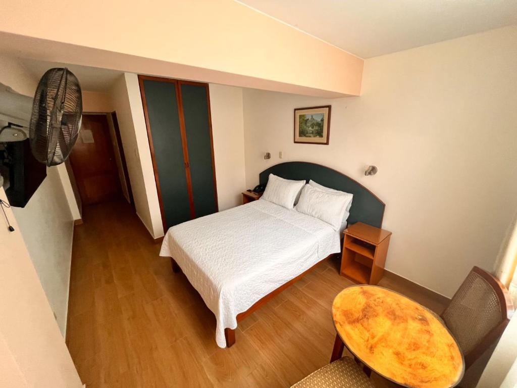 a bedroom with a bed and a table and a chair at Hotel Anthony's in Lima