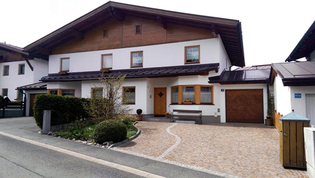 a white house with a wooden roof and a driveway at Haus Aschenwald in Kitzbühel