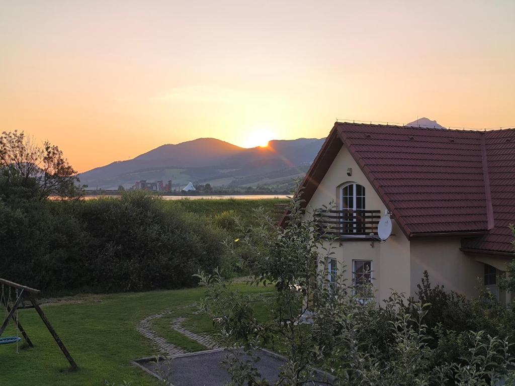 a house with the sunset in the background at Villa Rezort Vlašky in Bešeňová
