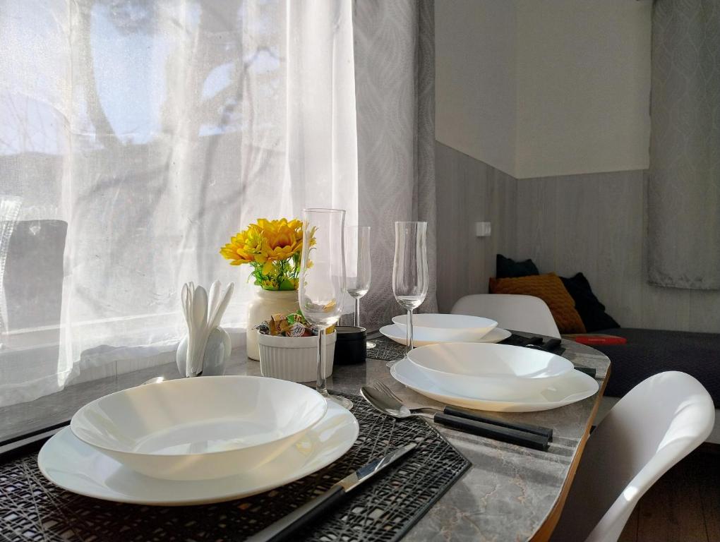 a table with white plates and wine glasses on it at Koidula Tiny House in Narva-Jõesuu